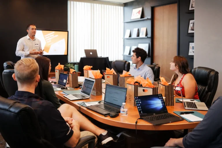 Salle de formation à Annecy avec un formateur et des adultes en apprentissage autour d’ordinateurs portables, dans une ambiance calme et bienveillante